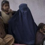 Malalai, center, from Kunduz province, sits with her children at a camp for internally displaced people as they wait for a bus to return home, in Kabul, Afghanistan