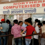 Passengers queue up at a ticket counter at a railway station