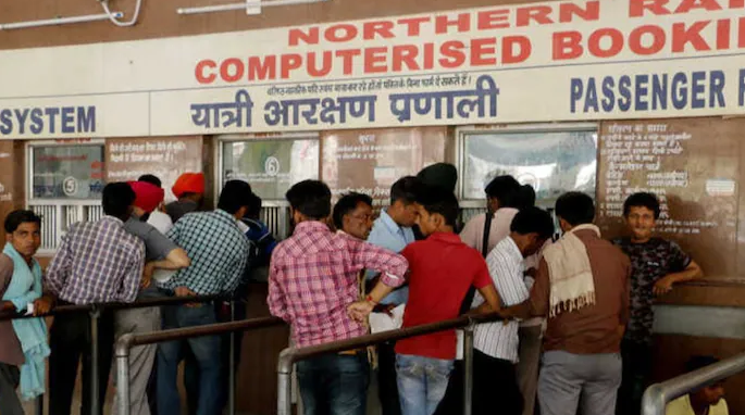 Passengers queue up at a ticket counter at a railway station