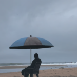 A lifeguard at Papanasam Beach in Varkala looks on at an overcast sky